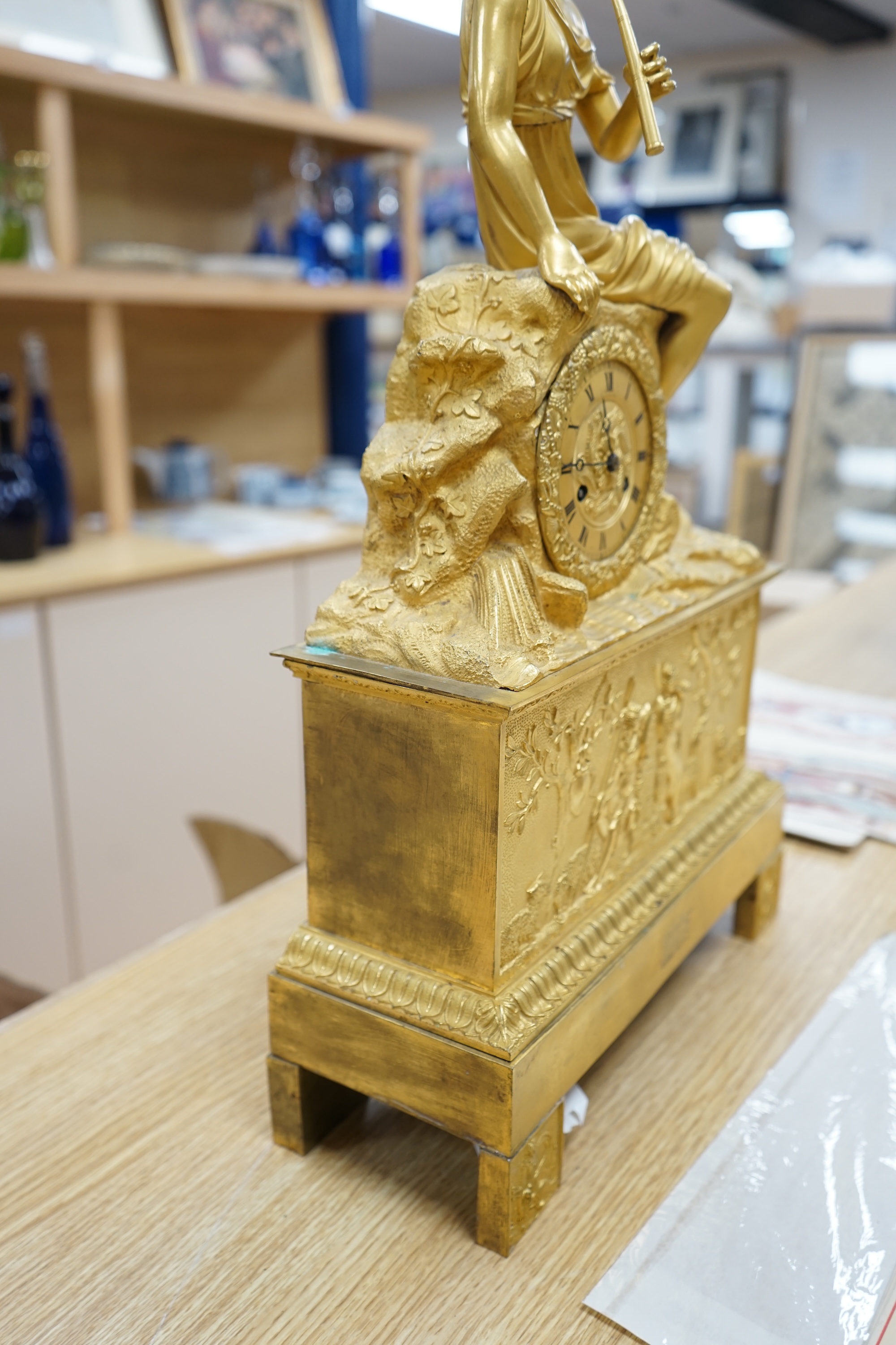 A French Louis Philippe period Empire ormolu clock, with seated classical female upon a rock enclosing the dial, the whole upon a square base with allegorical patch in relief, c.1830, with key, 57cm high. Condition - fai